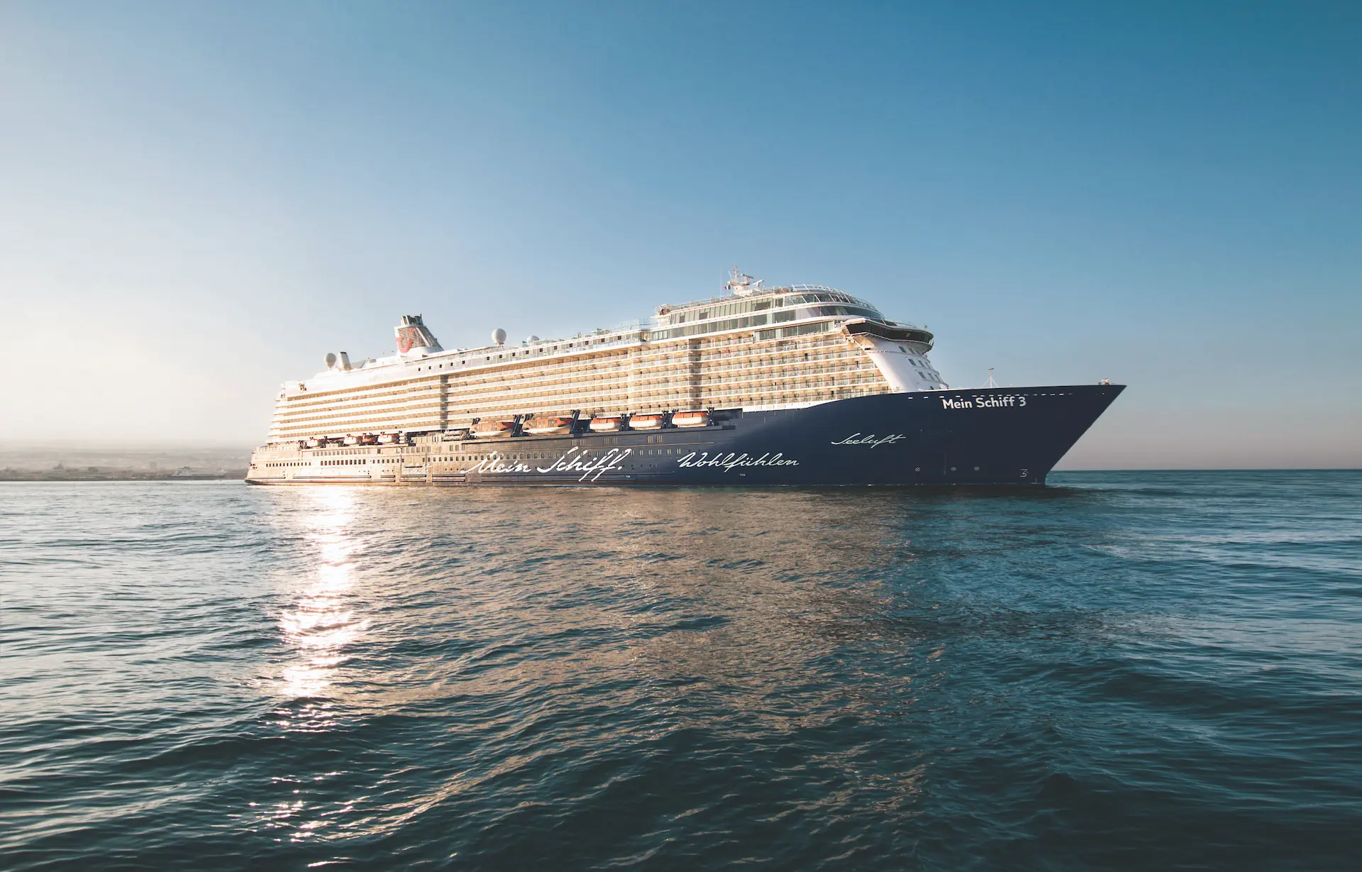Cruiseschip Mein Schiff 3 dat vaart op een rustige zee bij helder weer.