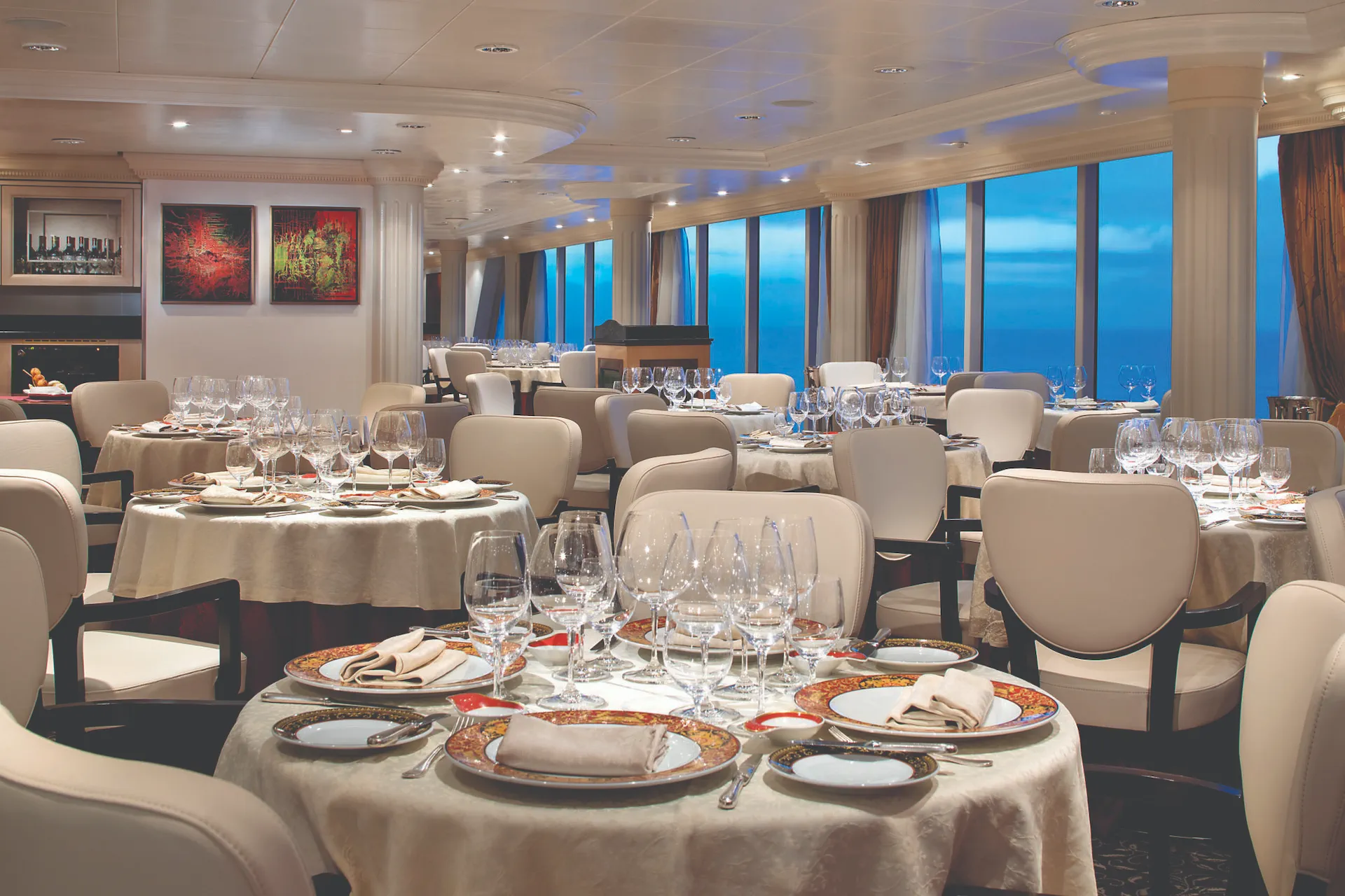 Eetzaal aan boord van Oceania Regatta met elegant gedekte tafels en grote ramen met zeezicht.