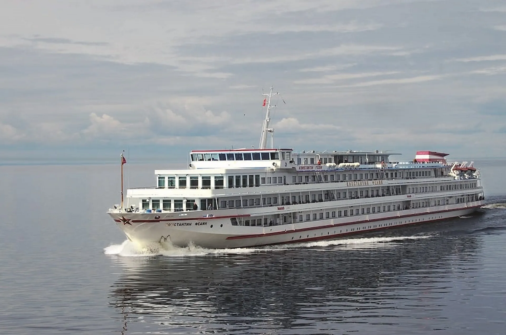 Het riviercruiseschip MS Fedin van Nicko Cruises vaart over rustig water onder een bewolkte lucht.