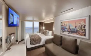 Modern interieur van de World Atlantic Balkonhut BA met een comfortabel bed, zithoek met bank en een panoramisch uitzicht op de oceaan.