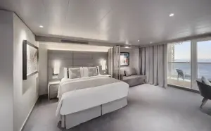 Luxe slaapkamer van de Grand Suite Aurea op de World Atlantic met een groot comfortabel bed en uitzicht op zee via het balkon.
