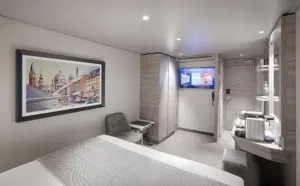 Interieur van een luxe Yacht Club binnenhut op de MSC World Atlantic met een groot bed, kunstwerk aan de wand en moderne voorzieningen.