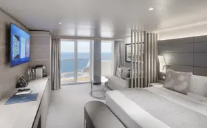 Interieur van een Yacht Club Deluxe Suite op de MSC World Atlantic met een tweepersoonsbed, zithoek, moderne roomdivider en privébalkon.