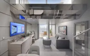 Moderne woonkamer van de Yacht Club Duplex Suite op de MSC World Atlantic met een grijze loungebank, grote TV en uitzicht op een privébalkon met whirlpool.