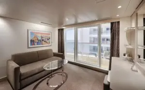 Modern interieur van de World Atlantic Premium Suite SLP met een comfortabele zitbank, glazen salontafel en uitzicht op het privébalkon.