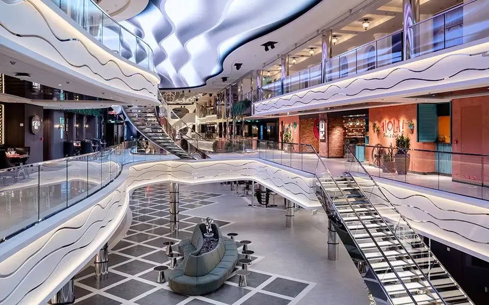 Winkelpromenade aan boord van het MSC World Asia cruiseschip met winkels en verlichting