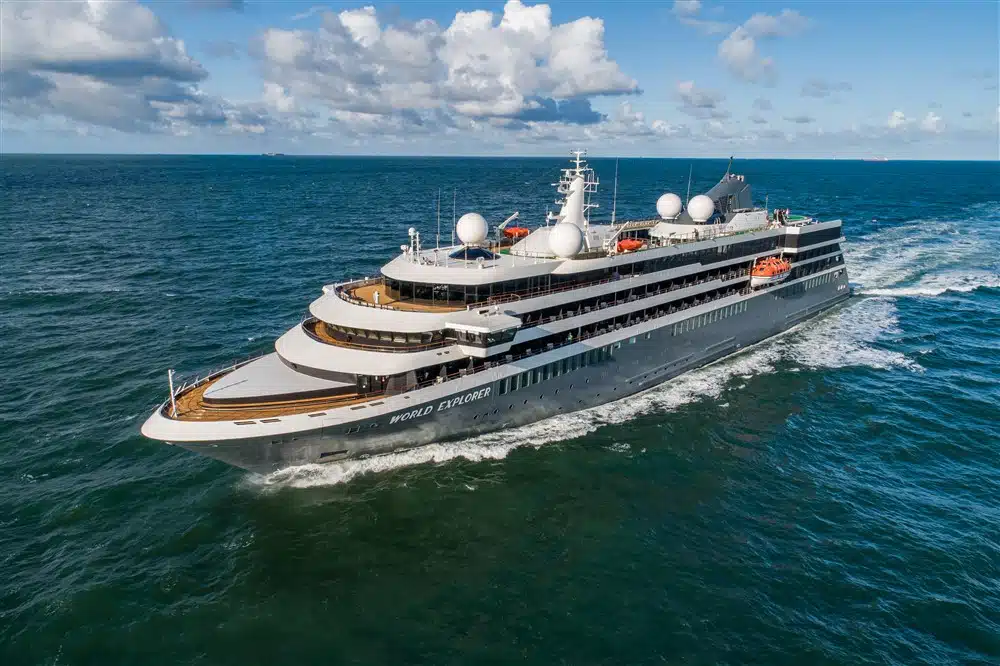 Het luxe expeditieschip World Explorer van rederij Rivages du Monde vaart op een diepblauwe zee onder een lichtbewolkte lucht.